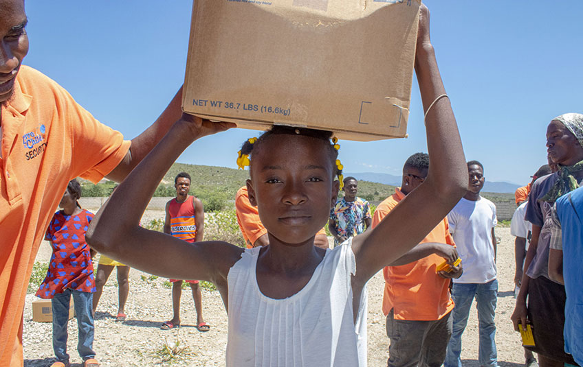 A girl holds a box of FMSC food on her head
