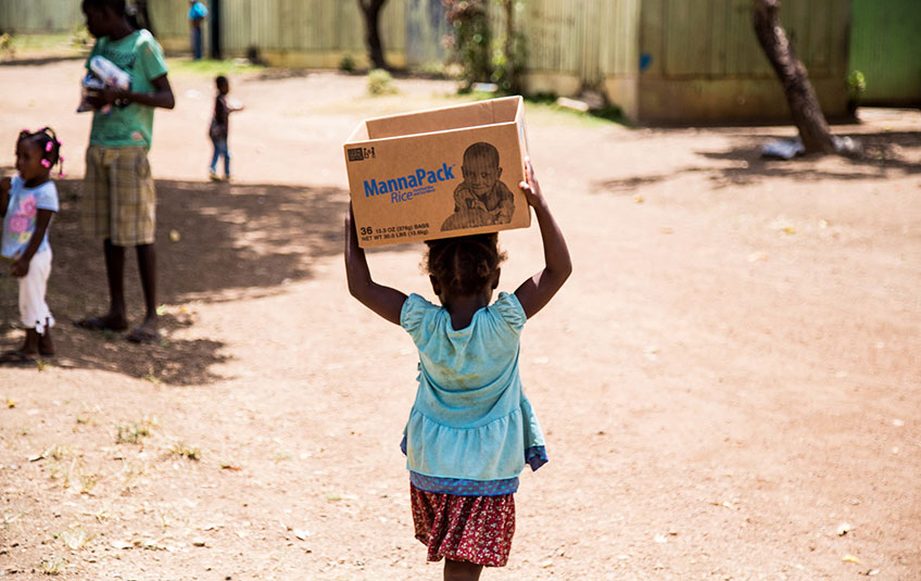 A little girl carries a box of FMSC food