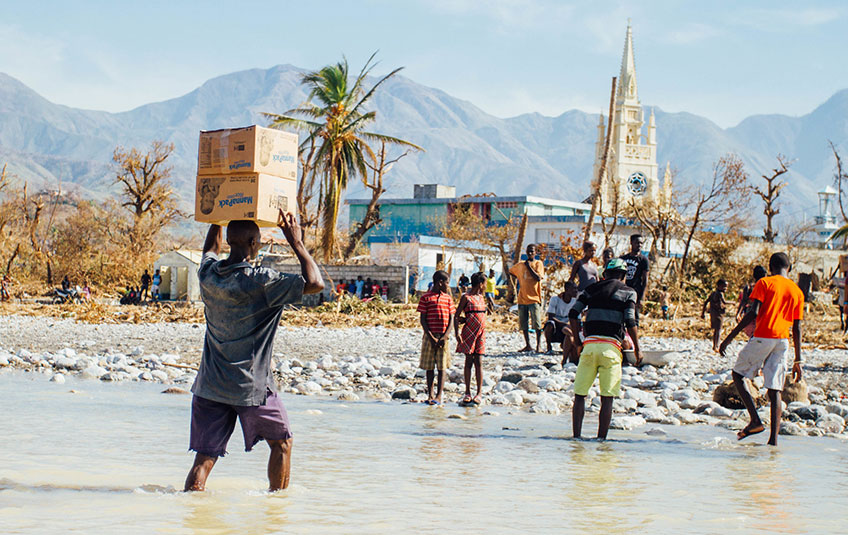 A group of Haitians carrying FMSC food across a river.