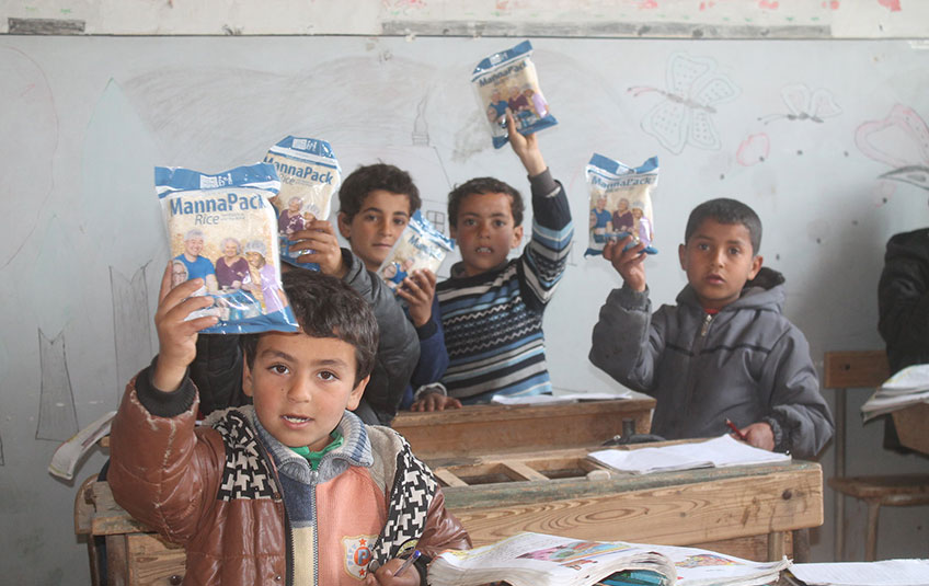 a group of children holds up MannaPack bags