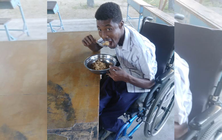A boy sitting in a wheelchair and eating FMSC food