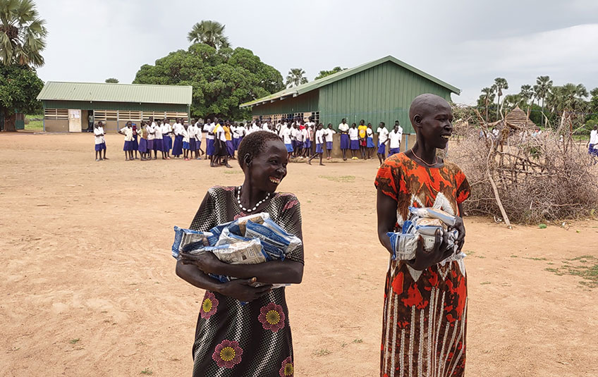 2 women with bags of food in their arms.