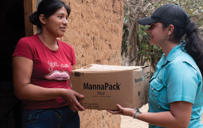 A woman hands another woman a box of FMSC food