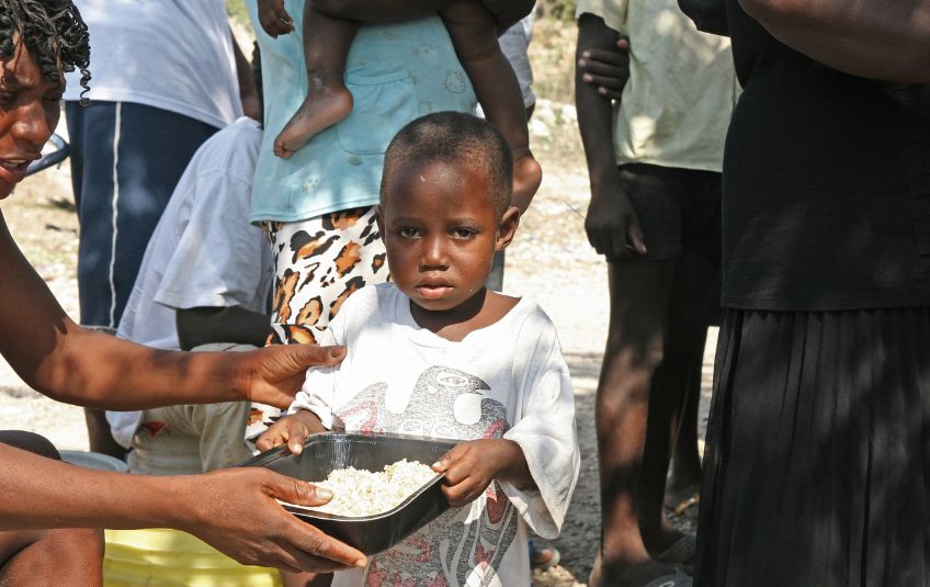 Haitian child being handed bowl of rice