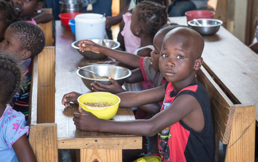 Children at desks with bowls of food