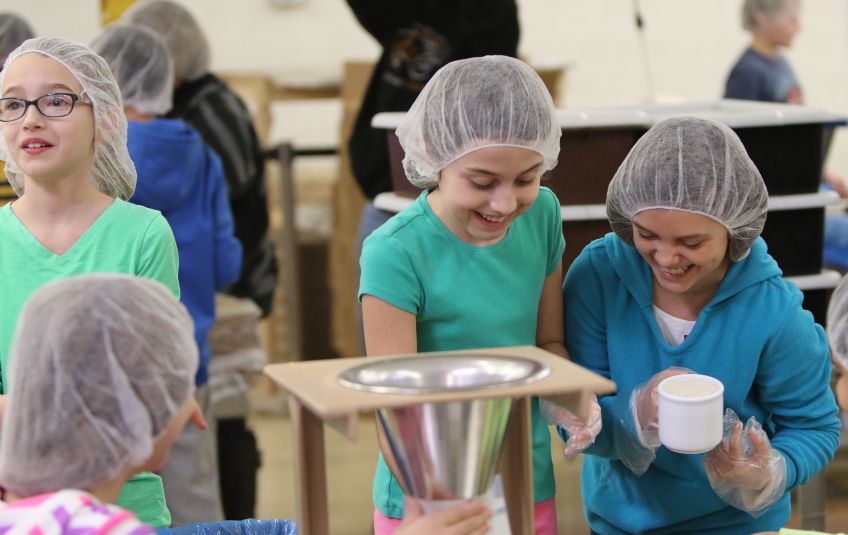 girls in hairnets packing meals