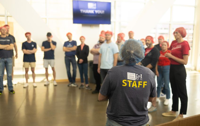 FMSC staff member speaking to a group of volunteers in hairnets
