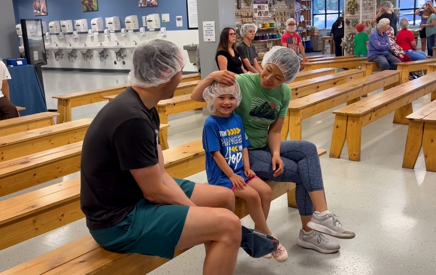 Family volunteer opportunity parents and daughter in hairnets at Feed My Starving Children