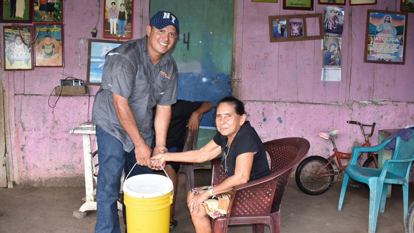 A man in FMSC's food program hands a bucket to an elderly woman