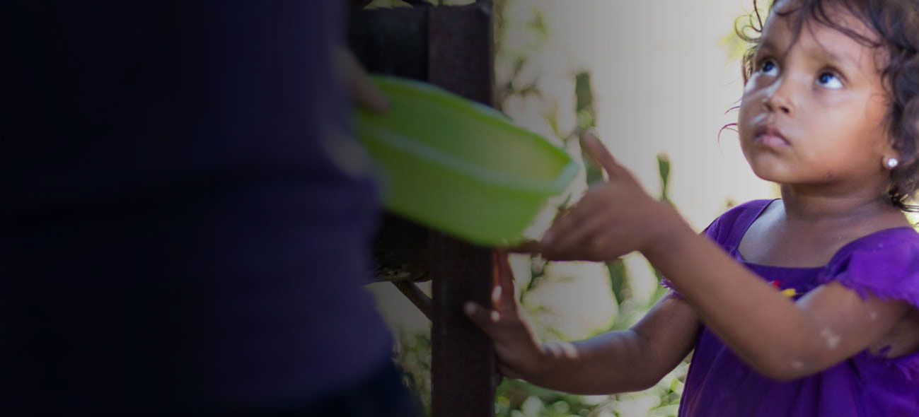 A girl hands an adult a bowl to be filled with FMSC food.