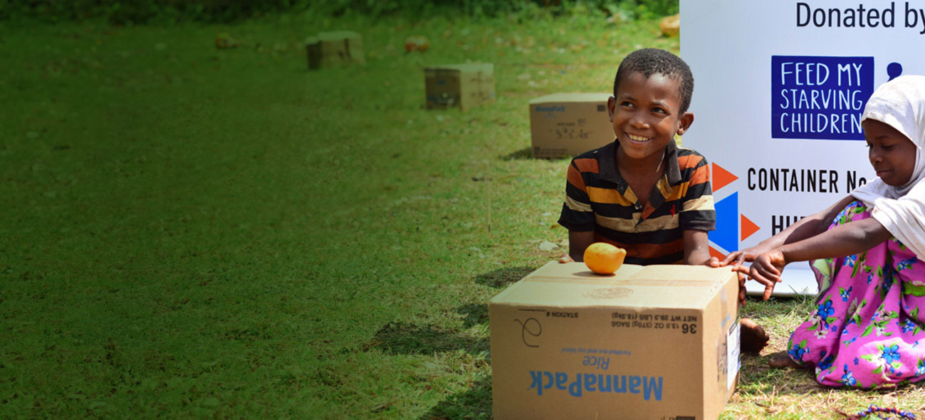 A boy and girl in sitting behind an FMSC food box